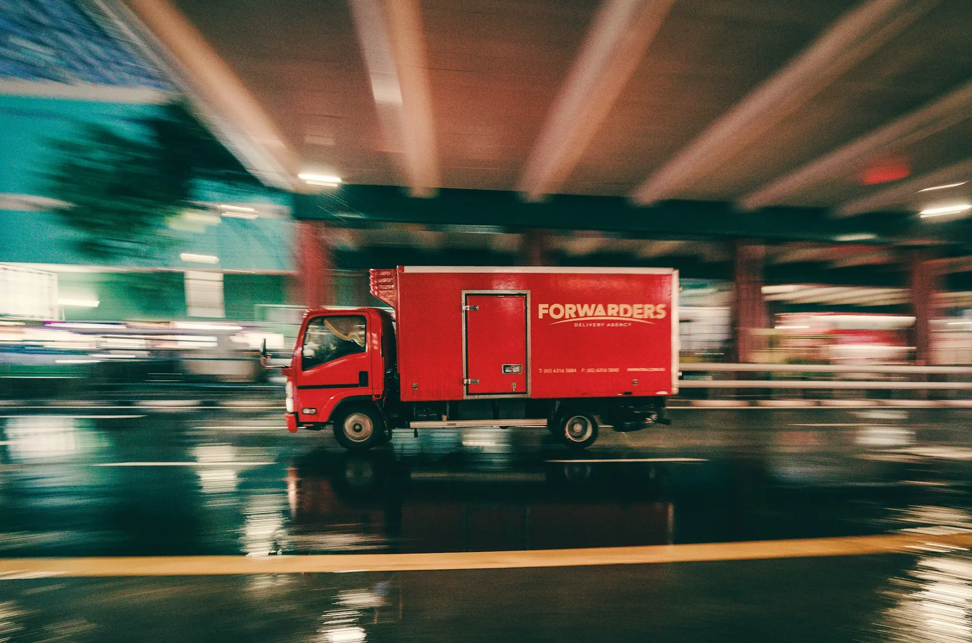 a red truck driving down a wet street